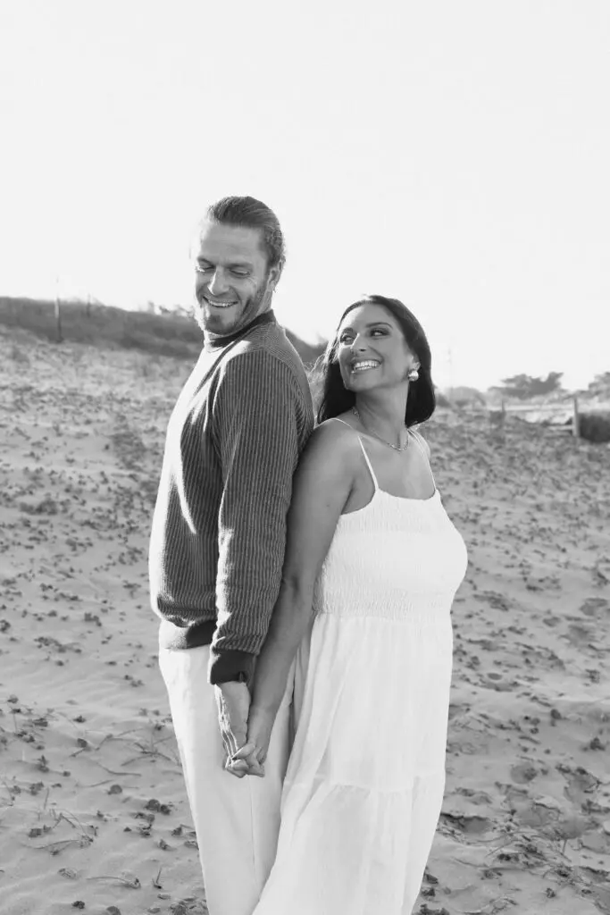 Black and white photo at a virginia beach engagement shoot where a couple is back to back 
