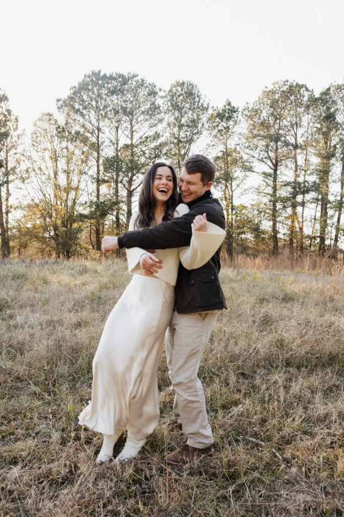 Couple standing face to face in a grassy field at Bells Mill Park in Chesapeake, dressed in simple, neutral-colored clothing.