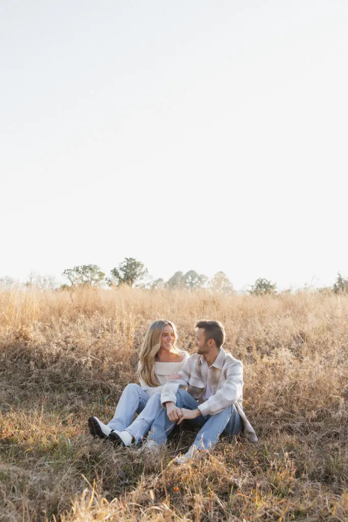 Engaged couple standing close together in a winter field at Bells Mills, Chesapeake, with soft neutral clothing and overcast skies.
