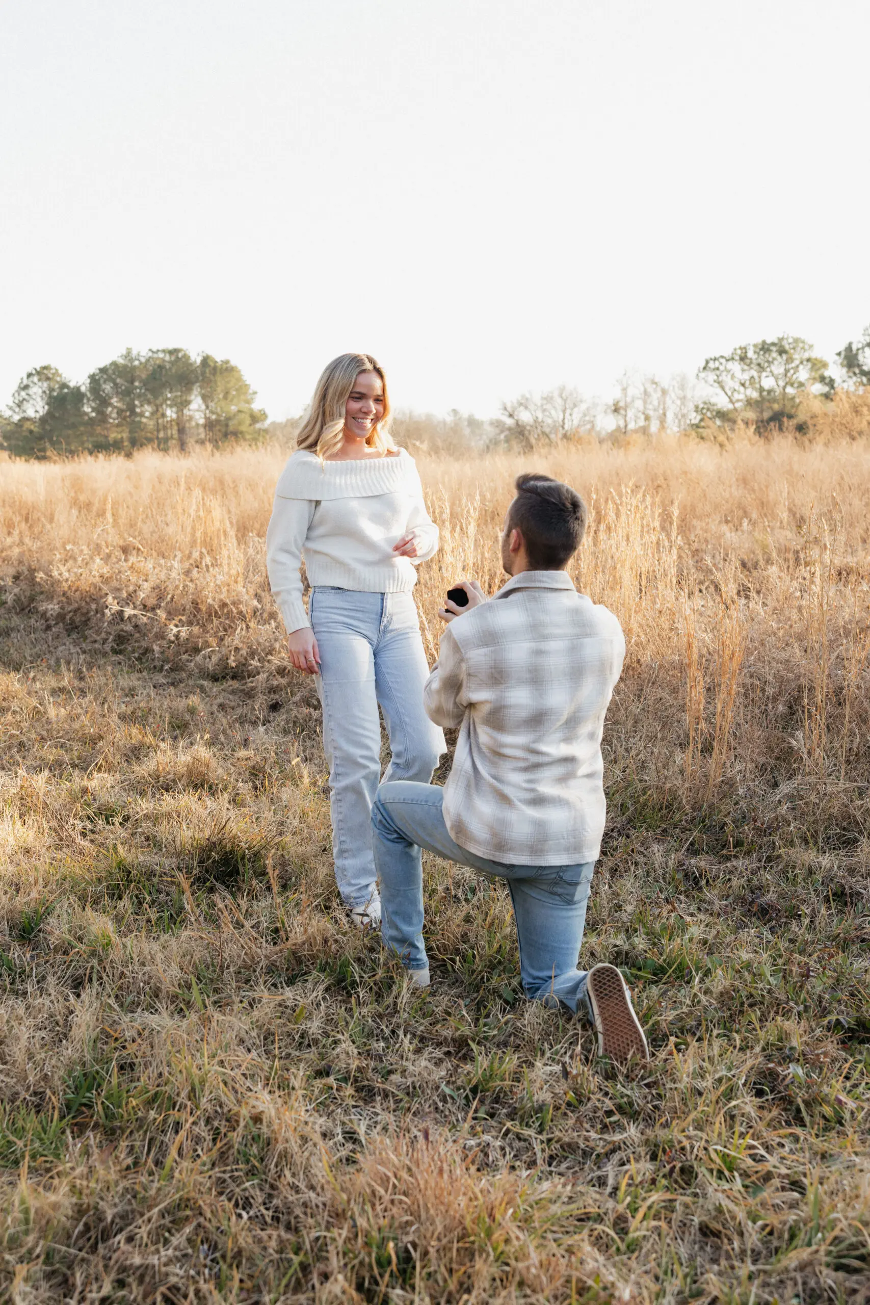man proposing to woman wearing winter neutrals in a grassy field in Virginia