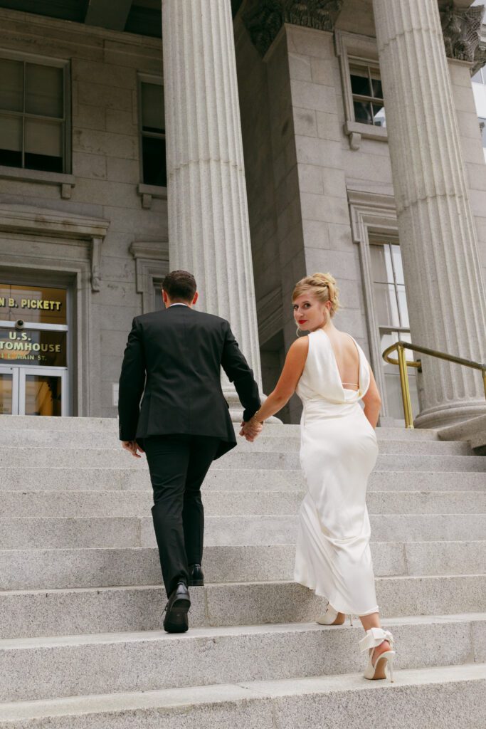 soon to be bride and groom walking up the custom house steps in downtonw norfolk