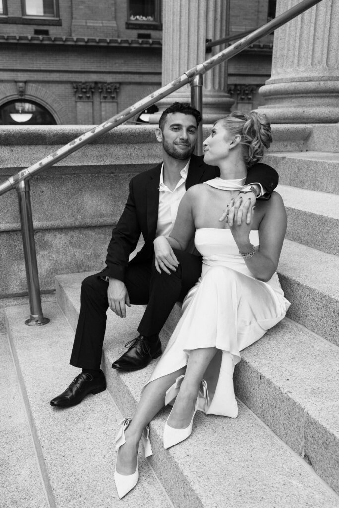 black and white image of a couple sitting on steps during a downtown norfolk engagement shoot