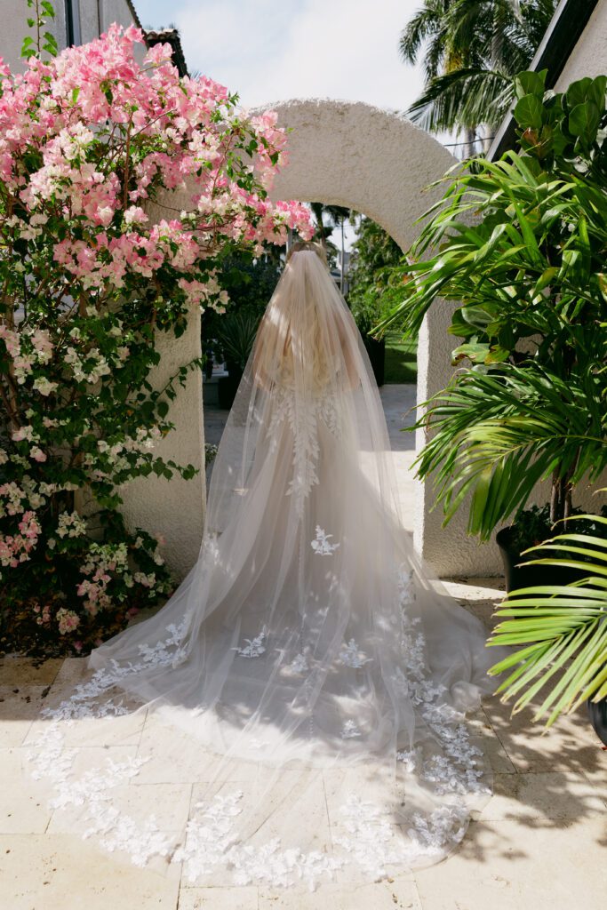 The bride walking away outside showcasing her long lace veil 