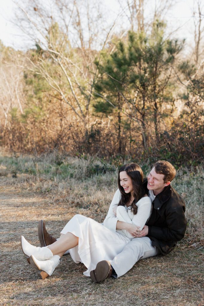 Couple embracing in a quiet field at Bells Mill Park, Chesapeake, Virginia, with tall grass and trees in the background.