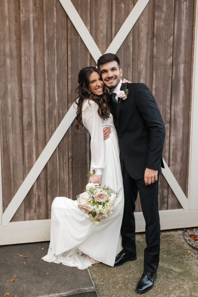 Newlyweds posing playfully in front of the vineyard landscape at Lovingston Winery near Charlottesville Virginia during their mountain wedding portrait session with blue ridge views