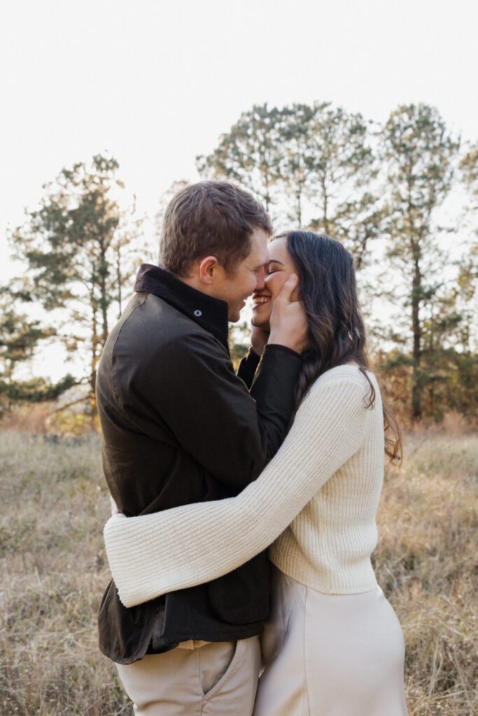 Engagement portrait of a couple strolling through a field at Bells Mill Park, dressed in coordinated neutral outfits