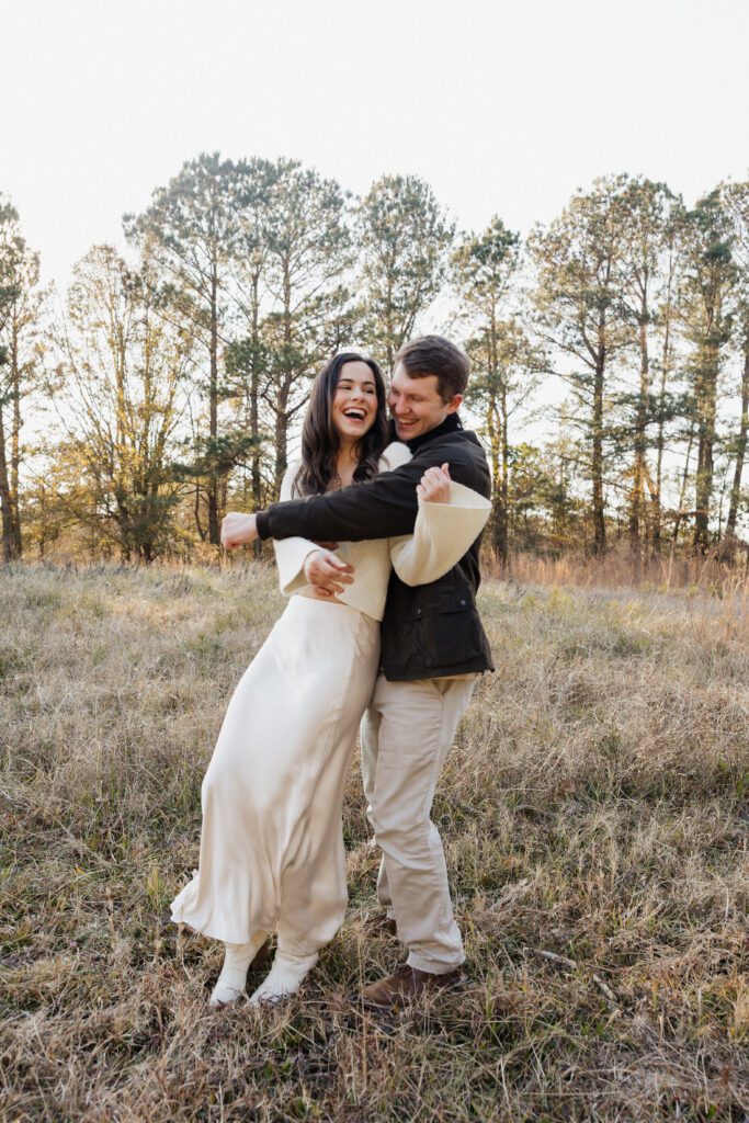 Couple standing face to face in a grassy field at Bells Mill Park in Chesapeake, dressed in simple, neutral-colored clothing.