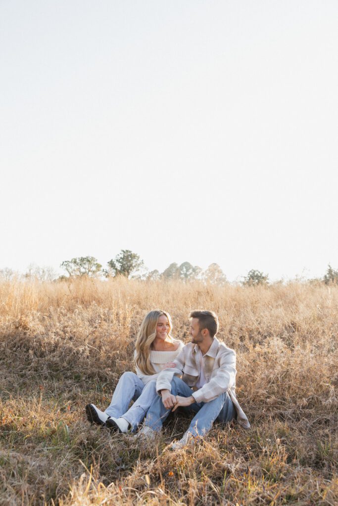 Engaged couple standing close together in a winter field at Bells Mills, Chesapeake, with soft neutral clothing and overcast skies.