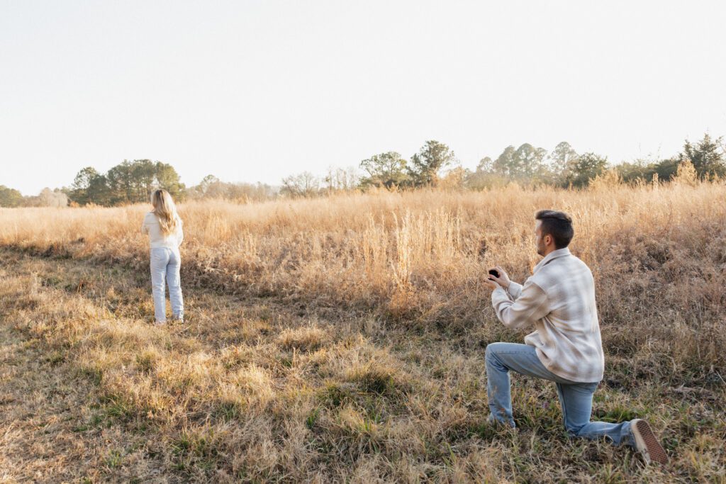 Couple celebrating their winter engagement in a grassy field at Bells Mills in Chesapeake, Virginia, wearing neutral-toned outfits.