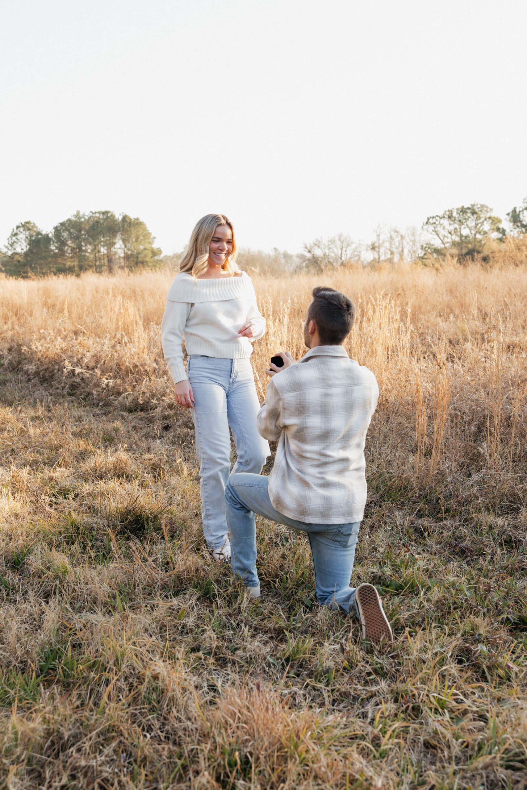 man proposing to woman wearing winter neutrals in a grassy field in Virginia