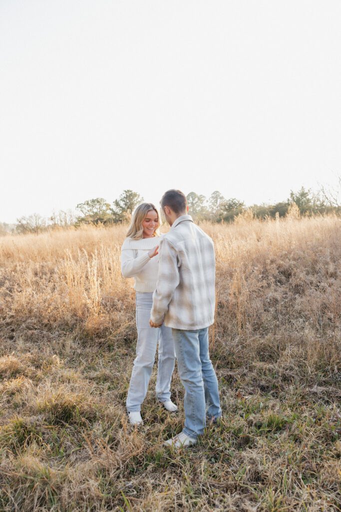 Engaged couple walking hand in hand through a winter field at Bells Mills, Chesapeake, dressed in neutral colors.